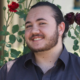 Person smiling to camera with roses in the background.